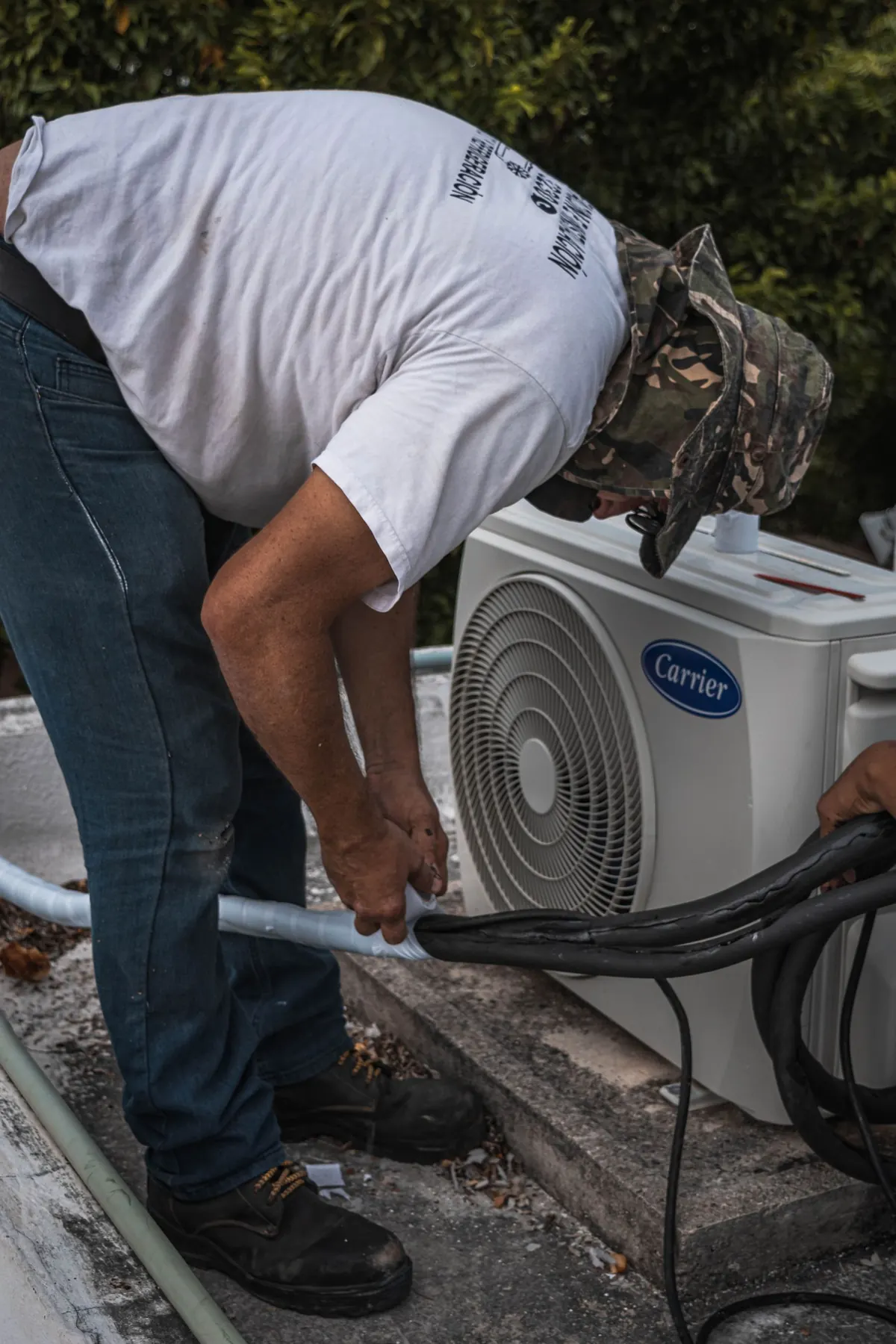 Technician connecting hoses on an outdoor AC unit